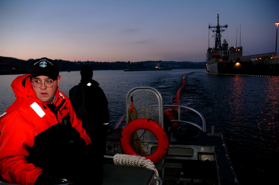 US Navy 050215-N-3390M-401 Engineman 3rd Class Johnny Thresh, left, and Engineman 3rd Class Johny Thresh, both assigned to Port Operations on board Naval Station Everett, position an oil containment boom around ships moored at