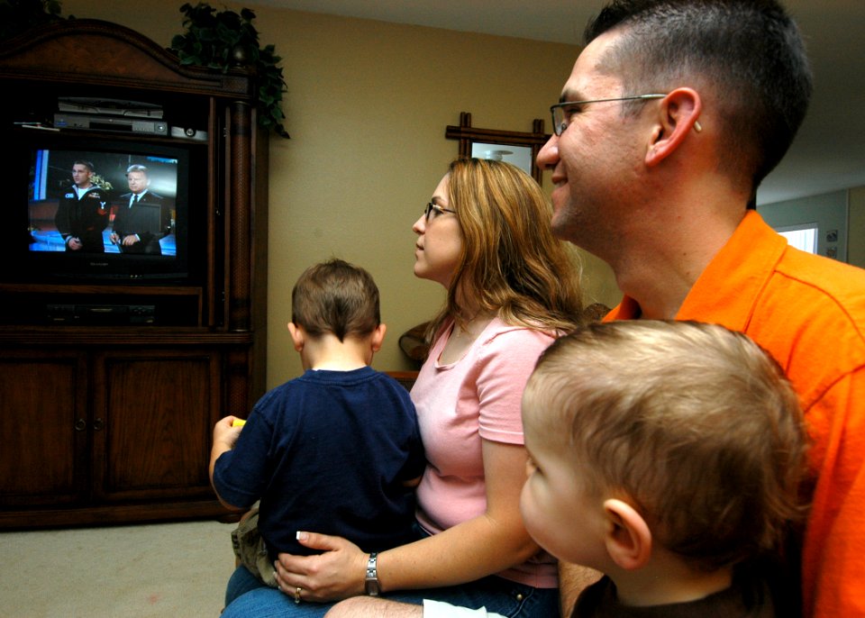 US Navy 050309-N-3019M-001 Personnelman 1st Class Drew Breeden, assigned to the Safeguard-class rescue and salvage ship USS Salvor (ARS 52), and his wife and two sons, watch a tape of Breeden playing the Wheel of Fortune game s