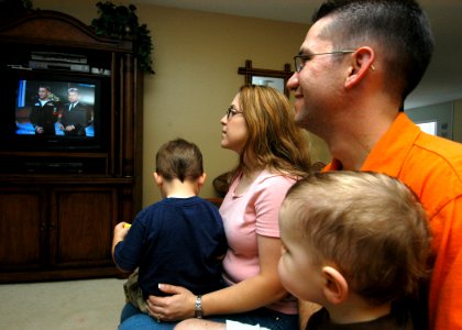 US Navy 050309-N-3019M-001 Personnelman 1st Class Drew Breeden, assigned to the Safeguard-class rescue and salvage ship USS Salvor (ARS 52), and his wife and two sons, watch a tape of Breeden playing the Wheel of Fortune game s