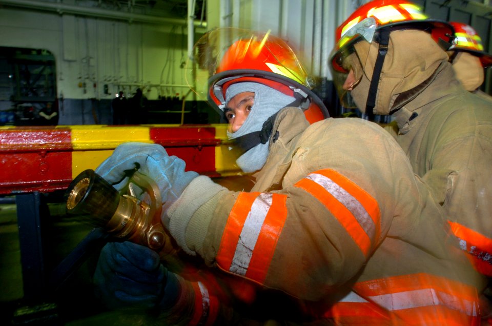 US Navy 050311-N-9866B-007 A Sailor moves the nozzle of a fire fighting hose back and forth to put out a simulated fire in the ship's hangar bay aboard the amphibious assault ship USS Peleliu (LHA 5), during a mass conflagratio