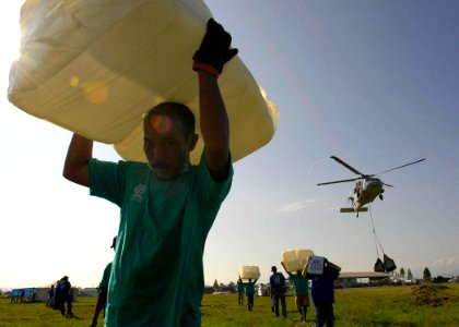 US Navy 050131-N-6074Y-110 Indonesian citizens carry plastic containers away from U.S. helicopter drop zone
