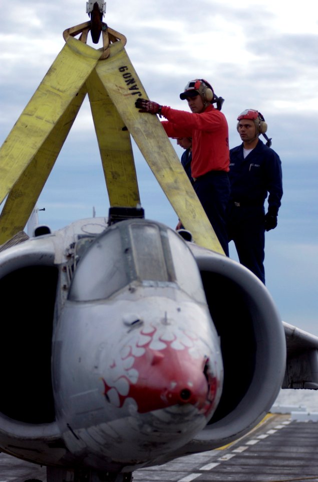 US Navy 050217-N-9866B-003 Aviation Boatswain's Mates work together on top of a AV-8A Harrier training aircraft as a crane hoist is attached to the aircraft during training drills on the flight deck aboard the amphibious assaul
