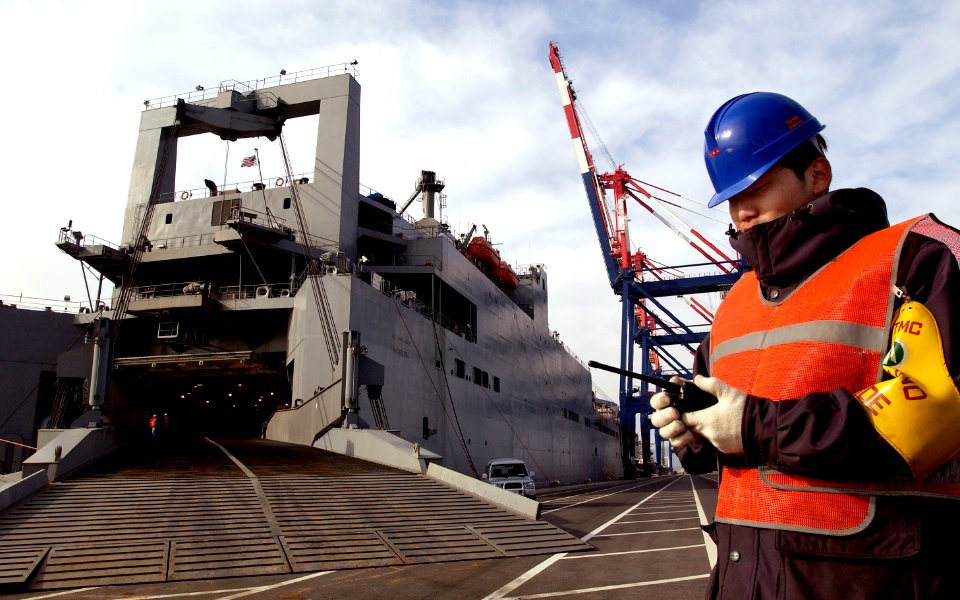 US Navy 050312-F-2902B-025 A Korean contractor uses a radio to contact his co-workers while loading a U.S. Army tracked vehicles aboard the Military Sealift Command (MSC) roll-on-roll-off shop USNS Watson (T-AKR 310)