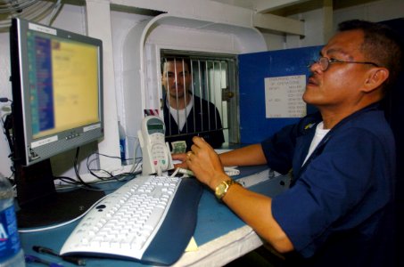 US Navy 050301-N-9866B-002 Disbursing Clerk 1st Class Gene Tecson checks the balance of a customer's Navy Cash Card account