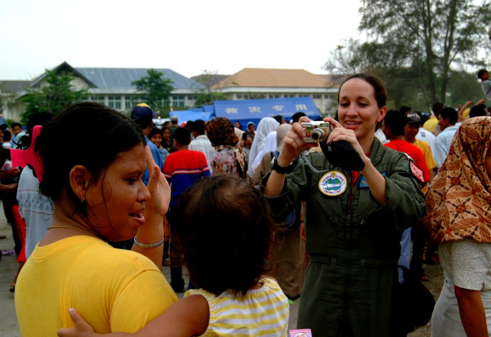US Navy 050214-N-0357S-063 Lt. Allison Johnson, assigned as Air Operations Officer aboard the Military Sealift Command (MSC) hospital ship USNS Mercy (T-AH 19), takes a photograph of an Indonesian women and her child