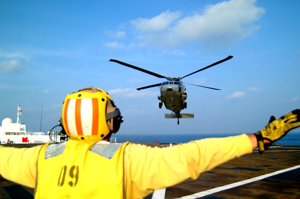 US Navy 050224-N-0357S-103 A Landing Signal Enlisted (LSE) guides a MH-60S Seahawk helicopter, assigned to Helicopter Combat Support Squadron Five (HC-5), for a landing aboard the Military Sealift Command (MSC) hospital ship U