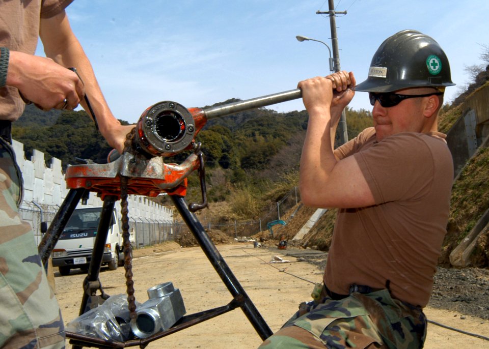 US Navy 050321-N-2385R-153 Construction Electrician 3rd Class Matthew Huston, assigned to Naval Mobile Construction Battalion Four Zero (NMCB-40), Detachment Sasebo, threads a pipe