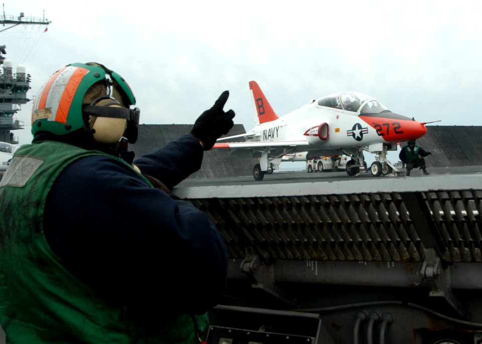 US Navy 050309-N-8704K-001 Aviation Boatswain's Mate 1st Class Robert McCray signals that the number one catapult is ready to launch a T-45A Goshawk