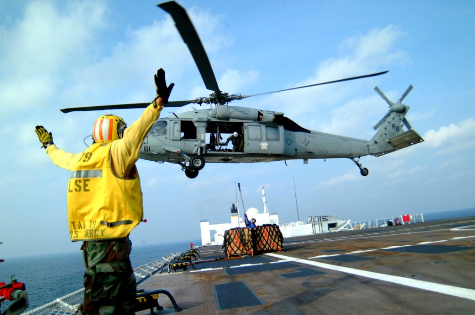 US Navy 050224-N-0357S-106 An MH-60S Seahawk helicopter, assigned to Helicopter Combat Support Squadron Five (HC-5), picks up boxes containing he personnel belongings of a group of healthcare workers from the non-governmental
