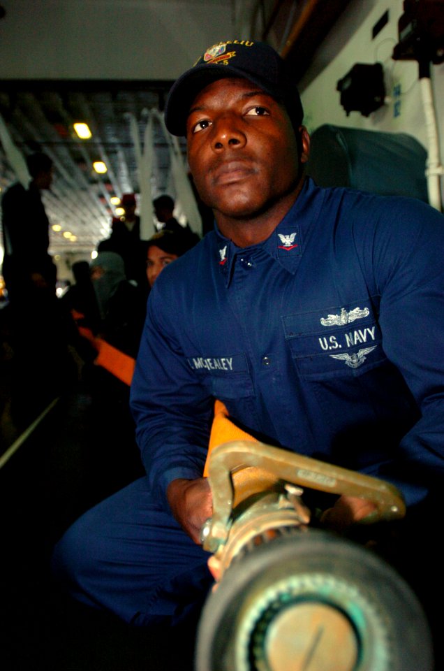 US Navy 050302-N-9866B-011 Boatswain's Mate 3rd Class Jai McNealey keeps a steady grip on a fire hose while awaiting orders to advance toward a simulated fire aboard the amphibious assault ship USS Peleliu (LHA 5)