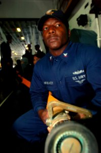 US Navy 050302-N-9866B-011 Boatswain's Mate 3rd Class Jai McNealey keeps a steady grip on a fire hose while awaiting orders to advance toward a simulated fire aboard the amphibious assault ship USS Peleliu (LHA 5)