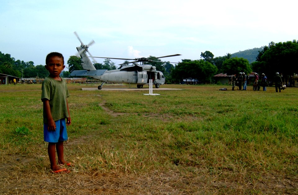 US Navy 050326-N-0357S-024 A young Indonesian child from the village of Bukapitung on the island of Alor, Indonesia, watches as Sailors unload medical supplies and equipment