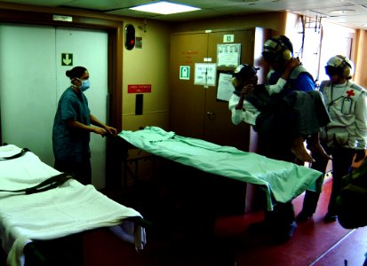 US Navy 050211-N-0357S-043 Machinist's Mate 2nd Class Christopher Atwater, a flight deck crew man aboard the Military Sealift Command (MSC) hospital ship USNS Mercy (T-AH 19), carries an elderly Indonesian man to a stret photo