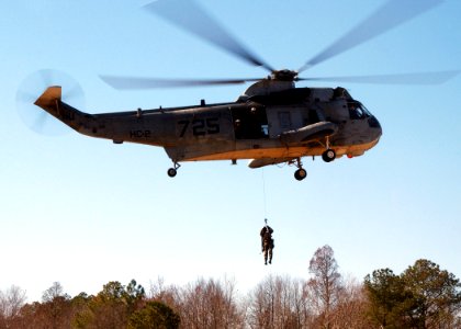 US Navy 050304-N-4374S-002 A member of Explosive Ordnance Disposal Mobile Unit Six (EODMU-6) is hoisted down to perform a Combat Search and Rescue (CSAR) exercise from a UH-3H Sea King helicopter