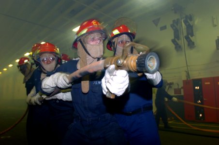 US Navy 050311-N-9866B-013 A fire fighting team works together to put out a simulated fire in the ship's hangar bay aboard the amphibious assault ship USS Peleliu (LHA 5)