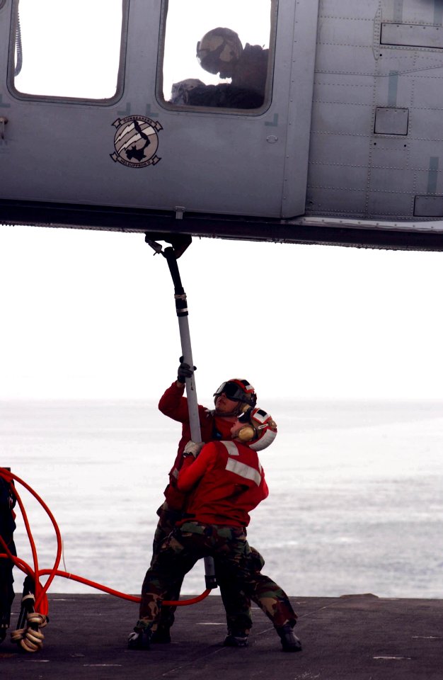 US Navy 050312-N-8158F-048 During a Vertical Replenishment (VERTREP), crew members aboard USS Nimitz (CVN 68), attach cargo pendant to a SH-60 Seahawk