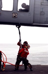 US Navy 050312-N-8158F-048 During a Vertical Replenishment (VERTREP), crew members aboard USS Nimitz (CVN 68), attach cargo pendant to a SH-60 Seahawk