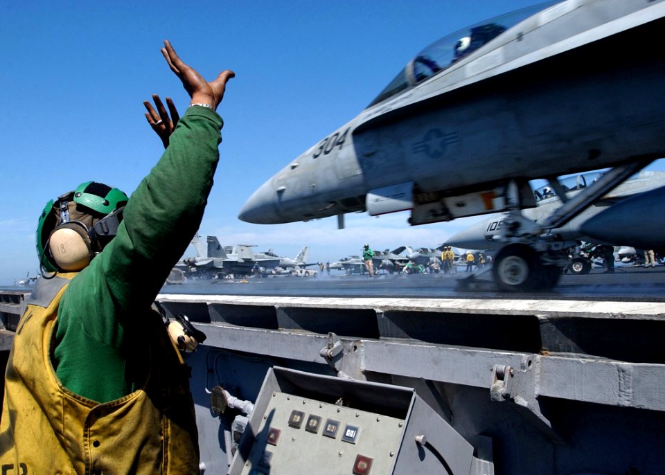 US Navy 050315-N-6363M-005 Aviation Boatswain's Mate 2nd Class Dennis Cochran, assigned to the Air Department as a waist safety observer, watches as an F-A-18C Hornet launches from the flight deck aboard USS Harry S. Trum