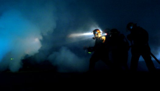 US Navy 050317-N-9866B-004 A fire fighting team works in the darkness to put out a simulated fire in the hanger bay of the amphibious assault ship USS Peleliu (LHA 5)