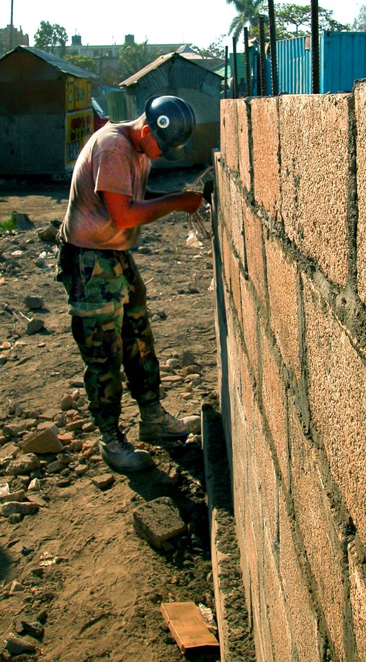 US Navy 050310-N-1464F-011 Builder Constructionman Apprentice Dustin Baugus, assigned to Naval Mobile Construction Battalion One (NMCB-1), lays bricks to construct a new three-room schoolhouse for children in Gonaives, Haiti
