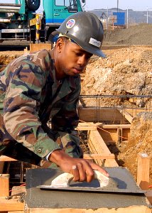 US Navy 050321-N-2385R-005 Engineering Aide Constructionman Doug Gaffney, assigned to Naval Mobile Construction Battalion Four Zero (NMCB-40), Detachment Sasebo, uses a magnesium float to even out concrete