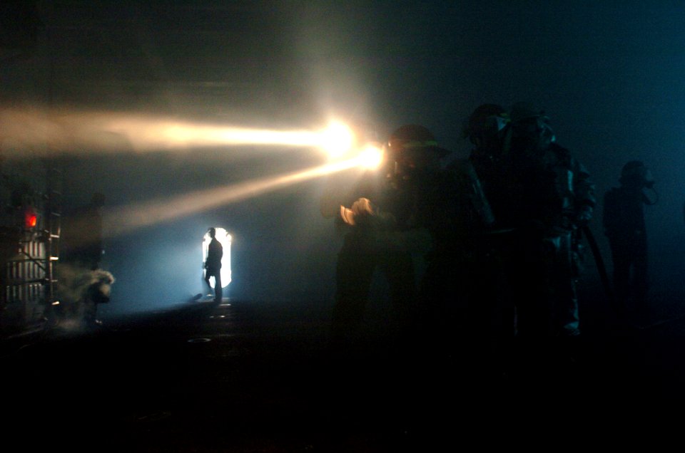 US Navy 050317-N-9866B-005 A fire fighting team works in the darkness to put out a simulated fire in the hanger bay of the amphibious assault ship USS Peleliu (LHA 5)