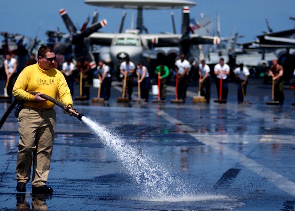 US Navy 050322-N-6363M-002 USS Harry S. Truman (CVN 75) Handler, Lt. Cmdr. George Sharp, sprays down the flight deck while Sailors line up to participate in a SCRUBEX