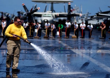 US Navy 050322-N-6363M-002 USS Harry S. Truman (CVN 75) Handler, Lt. Cmdr. George Sharp, sprays down the flight deck while Sailors line up to participate in a SCRUBEX