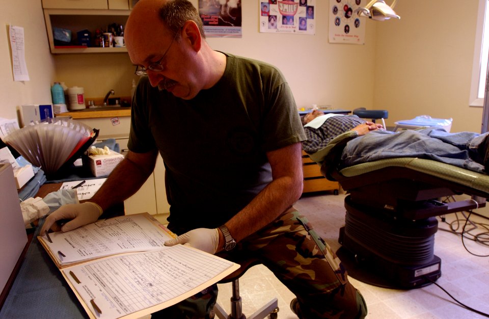 US Navy 050325-F-7169B-029 Navy Capt. Bruce Biermann, a dentist assigned to the Portland, Oregon Reserve Center, reviews the dental records of a Old Harbor resident