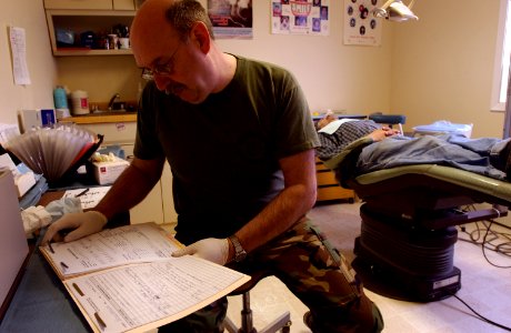 US Navy 050325-F-7169B-029 Navy Capt. Bruce Biermann, a dentist assigned to the Portland, Oregon Reserve Center, reviews the dental records of a Old Harbor resident