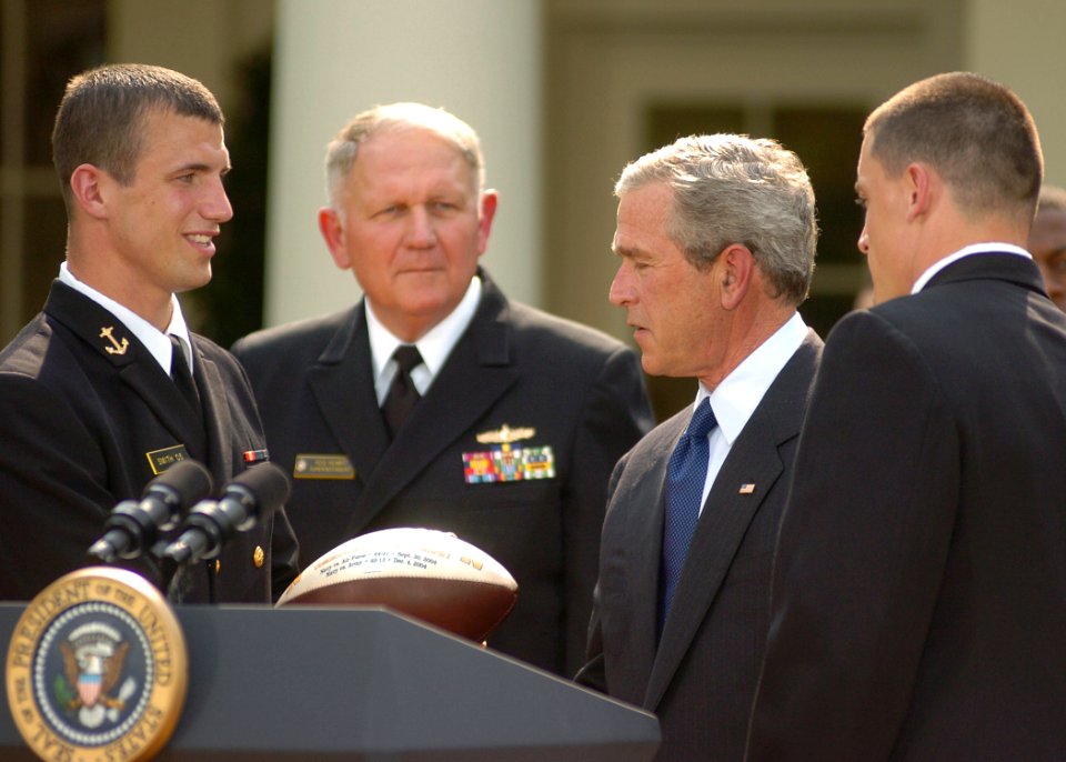 US Navy 050420-N-0000A-002 Midshipman 1st Class Josh Smith, left, presents a football to President George W. Bush during the presentation of the Commander-In-Chief's Trophy to members of the U.S. Naval Academy football team