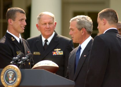 US Navy 050420-N-0000A-002 Midshipman 1st Class Josh Smith, left, presents a football to President George W. Bush during the presentation of the Commander-In-Chief's Trophy to members of the U.S. Naval Academy football team