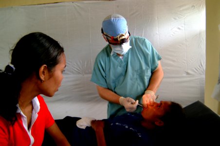 US Navy 050326-N-0357S-021 Cmdr. Mark Roback, a Navy dentist from the Military Sealift Command (MSC) hospital ship USNS Mercy (T-AH 19), speaking to his patient through an interpreter, tells her that the injection he is giving photo