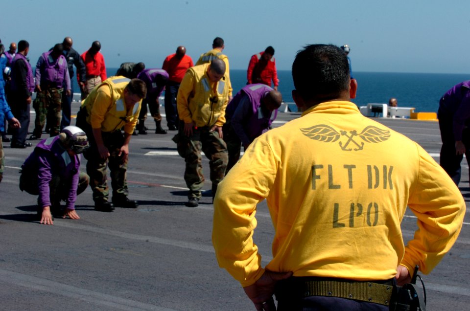 US Navy 050405-N-9866B-005 Flight Deck Leading Petty Officer, Aviation Boatswain's Mate 1st Class Reginald Anies, supervises Air Department personnel as they search the flight deck aboard the amphibious assault ship USS P