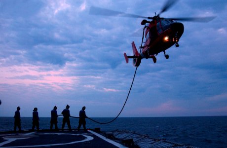 US Navy 050504-C-3721C-345 Crew members stationed aboard the U.S. Coast Guard Cutter Valiant (WMEC 621), pass a fuel line to an HH-65 Dolphin helicopter crew during a training exercise in the Gulf of Mexico