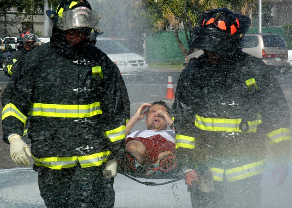 US Navy 050415-N-3019M-003 Federal Fire Department (FFD) firefighters carry a U.S. Navy Hospital Corpsman assigned to Naval Health Clinic, Makalapa, through a mass decontamination shower during a mass casualty-decontamination d