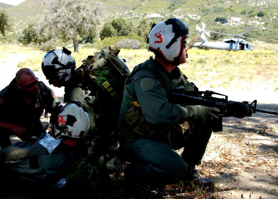 US Navy 050512-N-9500T-022 A helicopter crew chief stands guard while a medical technician examines a simulated casualty during Exercise Desert Steam