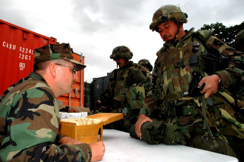 US Navy 050423-N-1722M-067 Builder 1st Class Robert Meech, assigned to Naval Mobile Construction Battalion Two Five (NMCB-25) turns in Chemical, Biological and Radiological (CBR) gear to Storekeeper 3rd Class Jeff Towls
