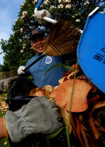 US Navy 050429-N-3019M-001 Chief Hospital Corpsman Perry Camagong, assigned to Navy Environmental and Preventive Medicine Unit Six (NEMPU-6), Pearl Harbor puts leaves into a trash bag