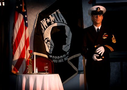 US Navy 050402-N-5134J-001 Chief Bret Pearson prepares to serve a glass of wine to the Prisoners of War-Missing in Action table