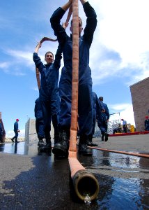 US Navy 050331-N-3019M-004 Sailors assigned to the guided missile frigate USS Crommelin (FFG 37) drain a fire hose after participating in a pipe patching exercise