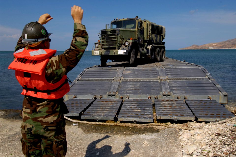 US Navy 050509-N-3642E-013 A Sailor assigned to the amphibious transport dock ship USS Austin (LPD 4) guides a five-ton truck from the Puerto Rican National Guard's 699th Engineering Company onto a causeway