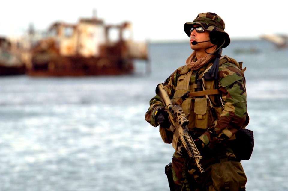 US Navy 050509-N-3642E-004 Aviation Structural Mechanic 2nd Class Aristoteli Dorizas assigned to Explosive Ordinance Disposal Mobile Unit Two (EODMU-2) provides force protection during the loading of equipment from Task Force N