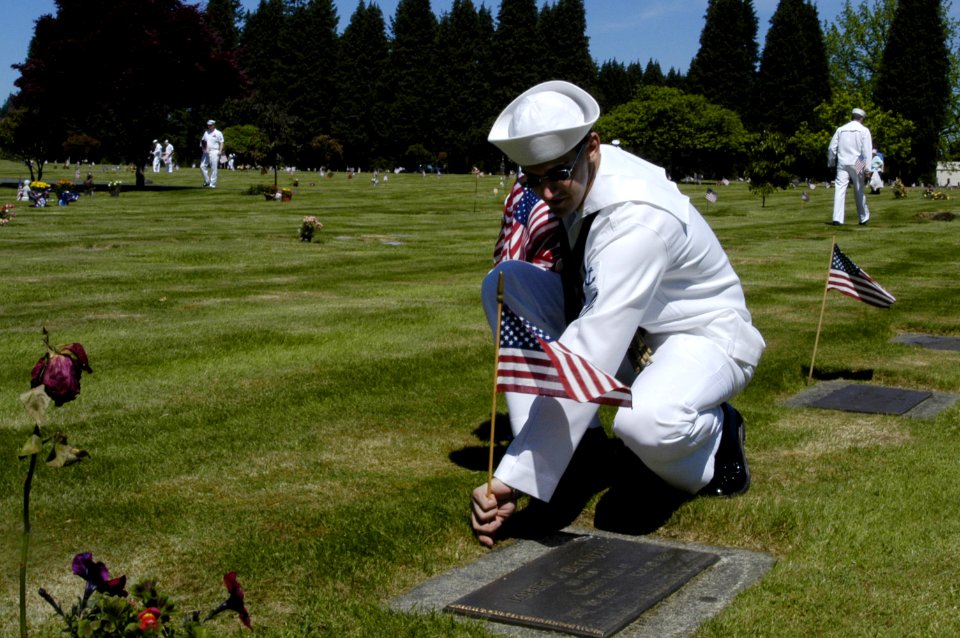 US Navy 050527-N-6477M-209 Seaman Christopher A. Racca, assigned to the Nimitz-class aircraft carrier USS Abraham Lincoln (CVN 72), places an American flag at the headstone of a veteran