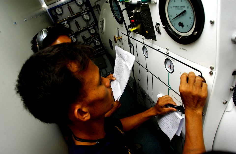 US Navy 050507-F-6335P-119 Royal Thai Navy divers from the Thai Diving School, check operation procedures set by U.S. Navy divers from the Mobile Diving Salvage Unit One (MDS-1), on a decompression chamber during exercise Cobra