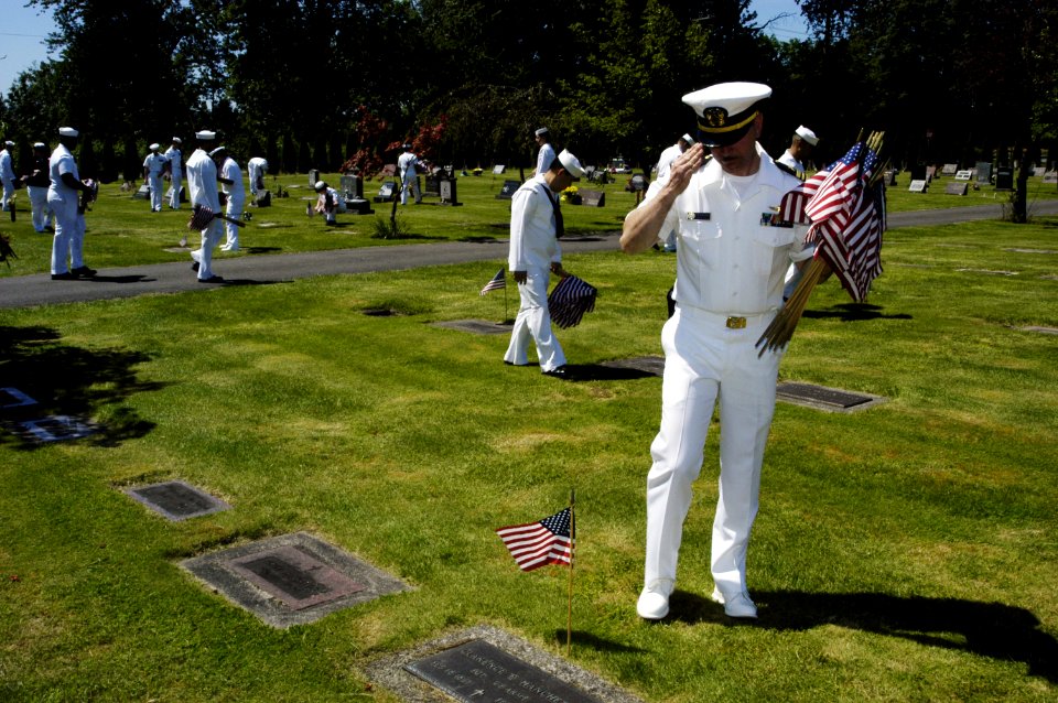 US Navy 050527-N-6477M-218 Naval Station Everett Chaplain, Lt. Cmdr. John M. Hakanson renders a salute after placing an American flag at the headstone of a veteran at the Grand Army of the Republic Cemetery in Snohomish, Wash