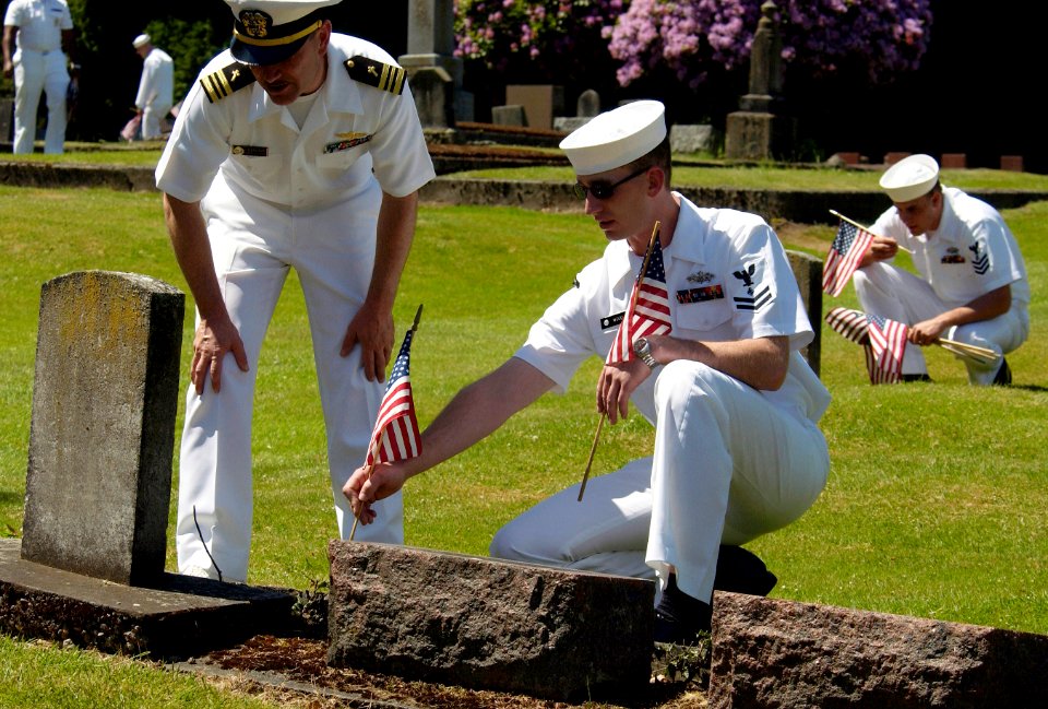 US Navy 050527-N-6477M-320 Naval Station Everett Chaplain, Lt. Cmdr. John M. Hakanson and Engineering Aide 2nd Class Daniel N. Wood, place an American flag at the headstone of a veteran