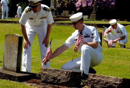 US Navy 050527-N-6477M-320 Naval Station Everett Chaplain, Lt. Cmdr. John M. Hakanson and Engineering Aide 2nd Class Daniel N. Wood, place an American flag at the headstone of a veteran photo