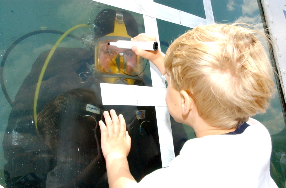 US Navy 050529-N-4729H-126 A young child plays tic-tac-toe with Aviation Warfare Systems Operator 1st Class Roger Martin, a member of one of the Navy's Explosive Ordnance Disposal (EOD) teams