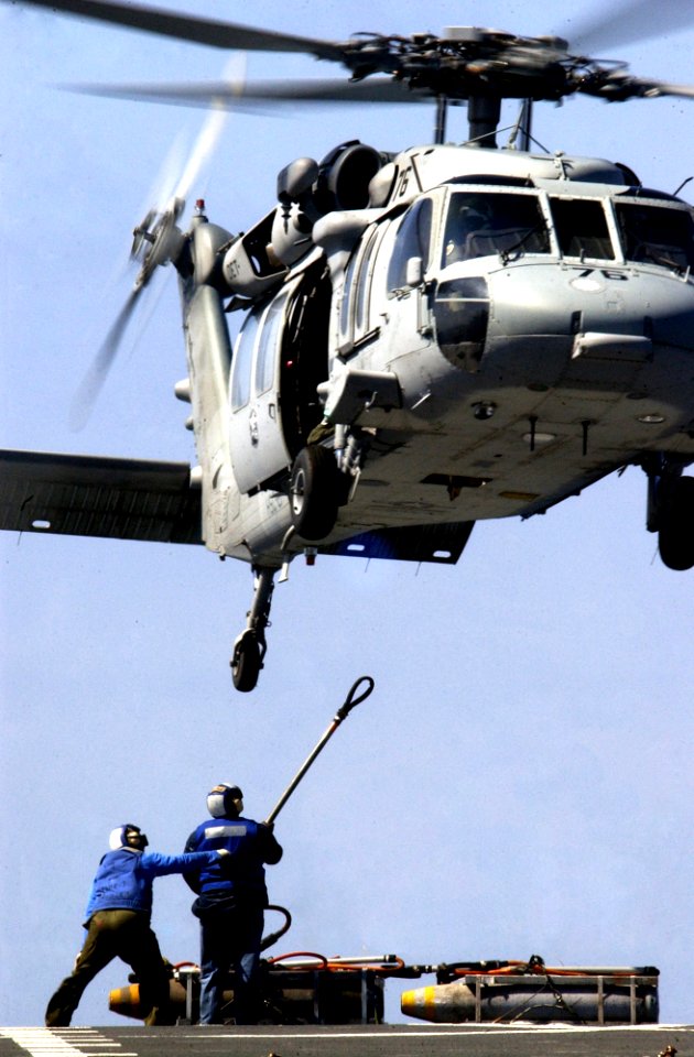 US Navy 050529-N-5549O-350 Sailors stationed aboard the Military Sealift Command (MSC) combat support ship USNS Rainier (T-AOE 7) prepare to load ordnance underneath an MH-60S Knighthawk
